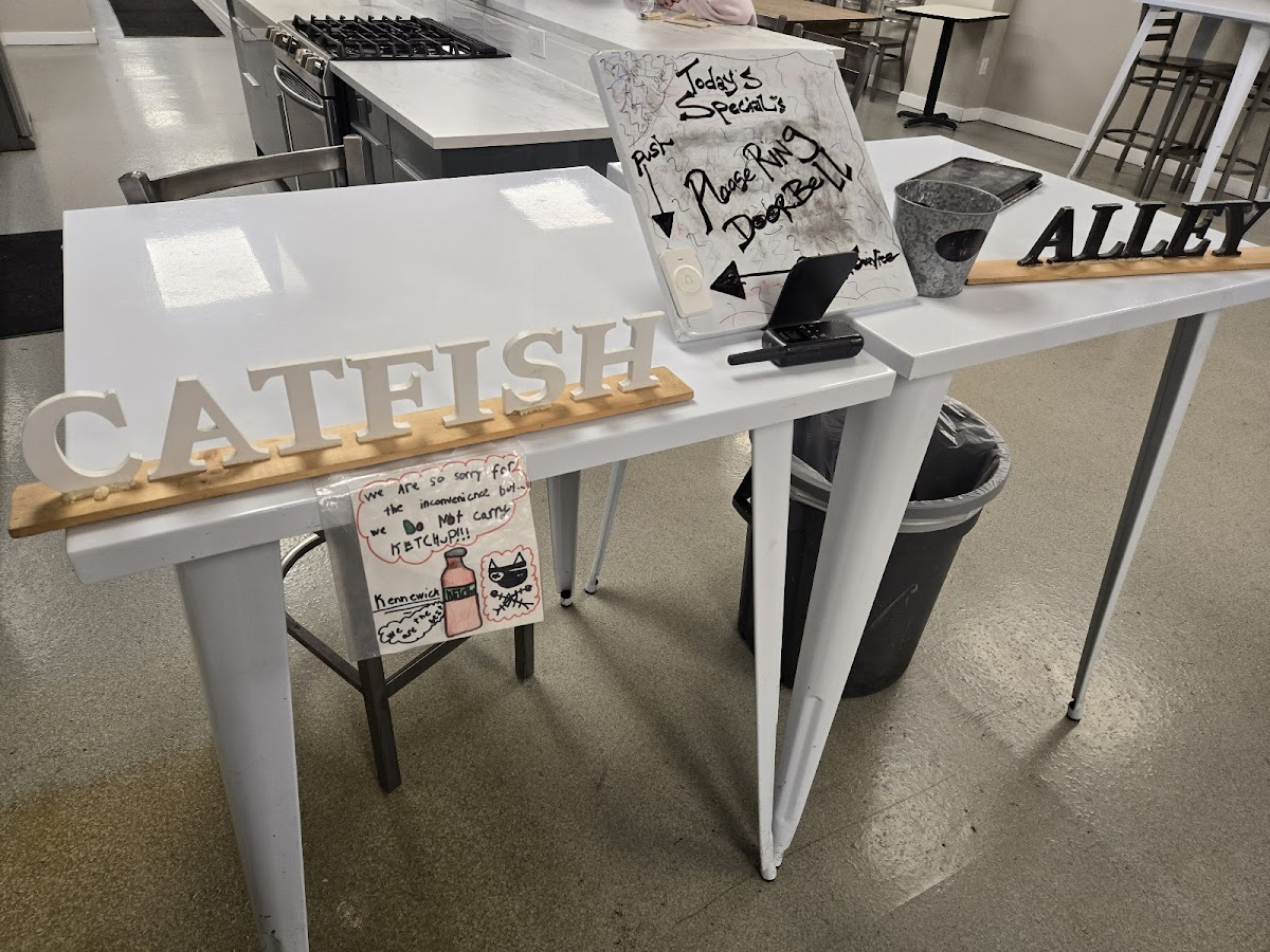 Hand-lettered Catfish Alley sign on a rustic counter inside the Kennewick restaurant